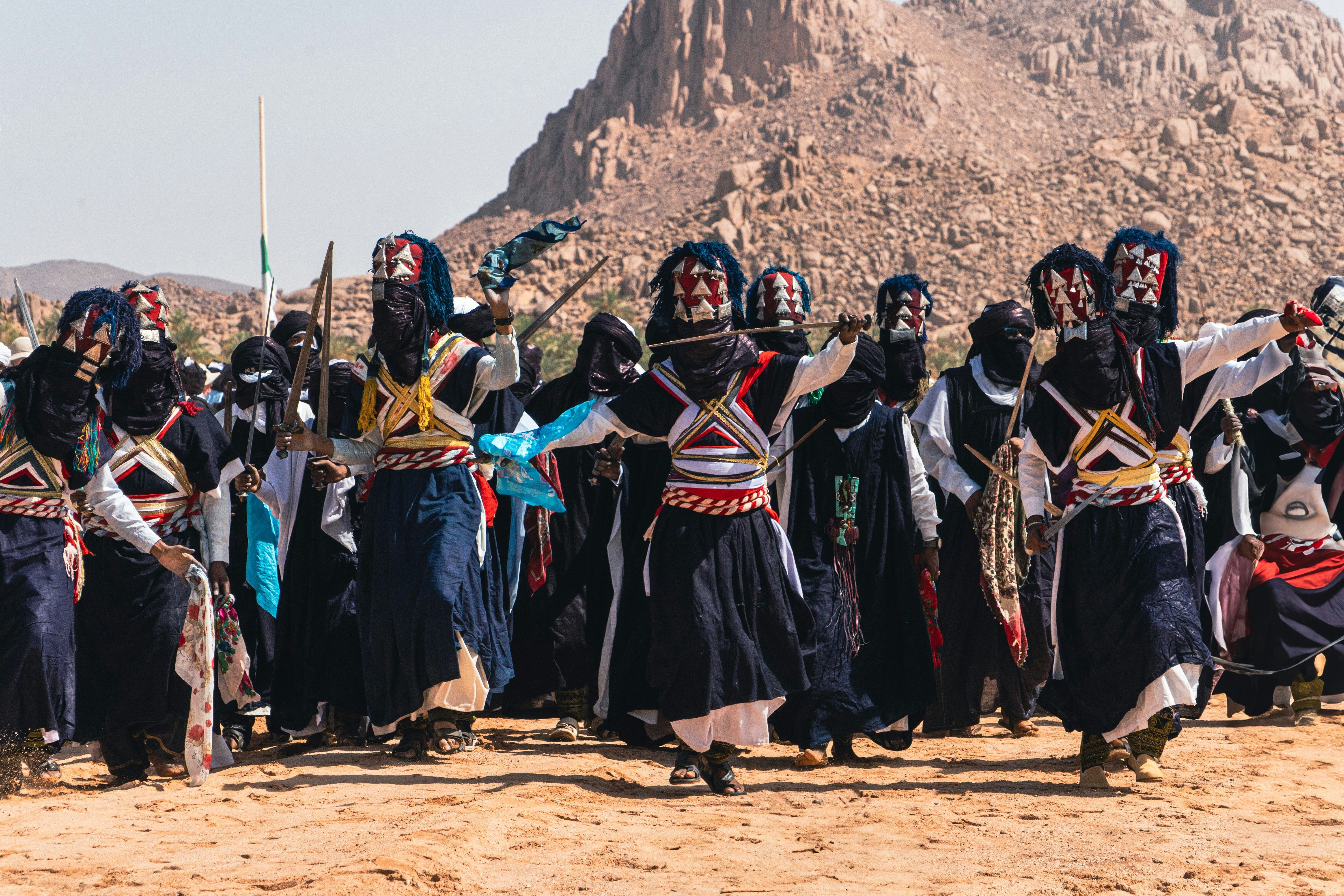 Performers in traditional dress against desert mountains near Djanet.